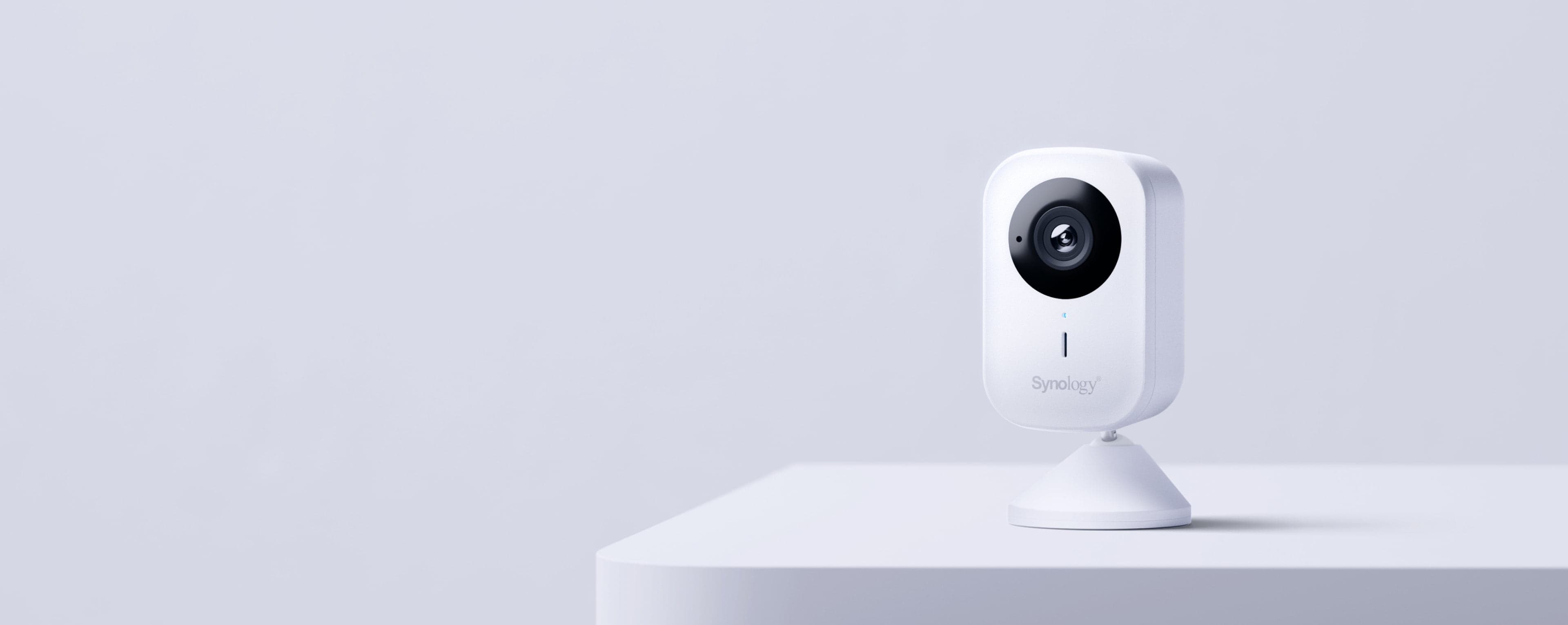 Synology CC410W Wi-Fi cube camera on its cone desk stand, three-quarter studio view - manufacturer product image; Synology serves this shot from its CC400W asset folder and uses it on the CC410W product page, the two models sharing one housing